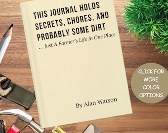 May include: A cream-colored journal with the text "THIS JOURNAL HOLDS SECRETS, CHORES, AND PROBABLY SOME DIRT... Just A Farmer's Life In One Place" and "By Alan Watson". The journal is surrounded by tools and a small patch of green foliage.