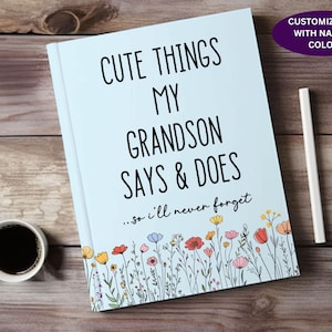 May include: A light blue journal with the text "Cute Things My Grandson Says & Does...so I'll never forget" in black. The journal is decorated with a border of colorful flowers.