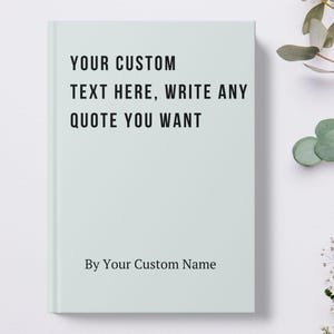 May include: A light blue journal with the text "YOUR CUSTOM TEXT HERE, WRITE ANY QUOTE YOU WANT" in black. The bottom of the journal reads "By Your Custom Name". The journal is closed and has a white spine.
