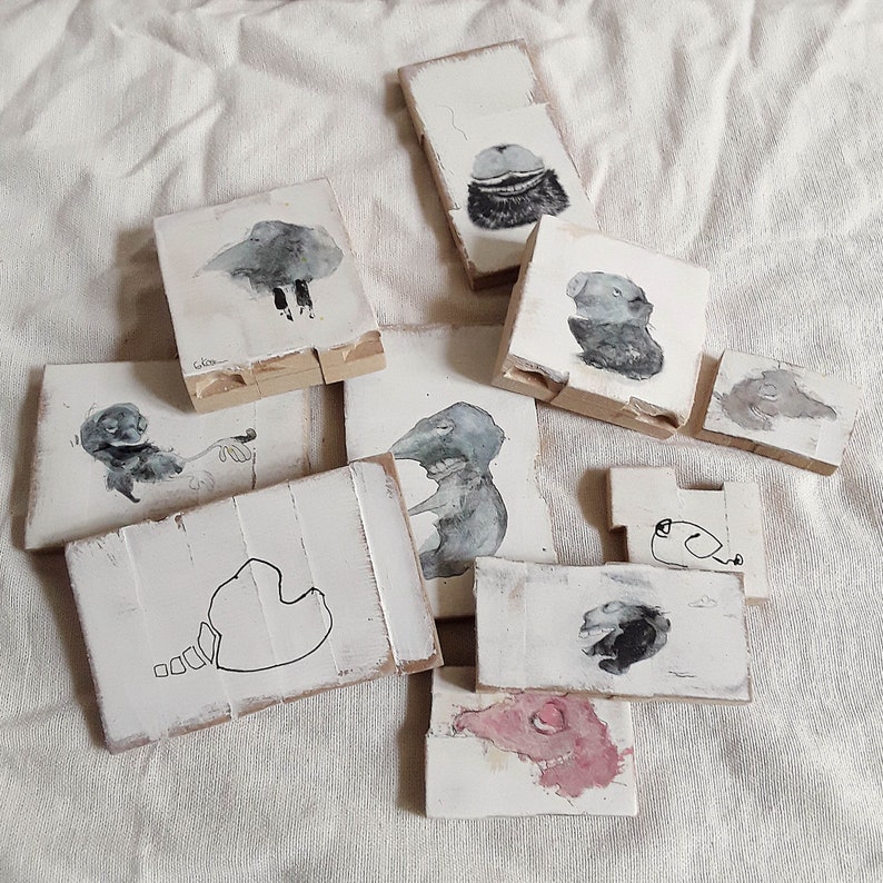 May include: A set of eight small wooden tiles with hand-painted illustrations of animals. Each tile features a different animal, including a bird, a bear, a rabbit, and a fox. The tiles are painted in a whimsical style with muted colors.