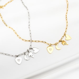 May include: Two necklaces with charms. One necklace is gold with a heart, crescent moon, and bird charms. The other necklace is silver with a heart, crescent moon, and bird charms.