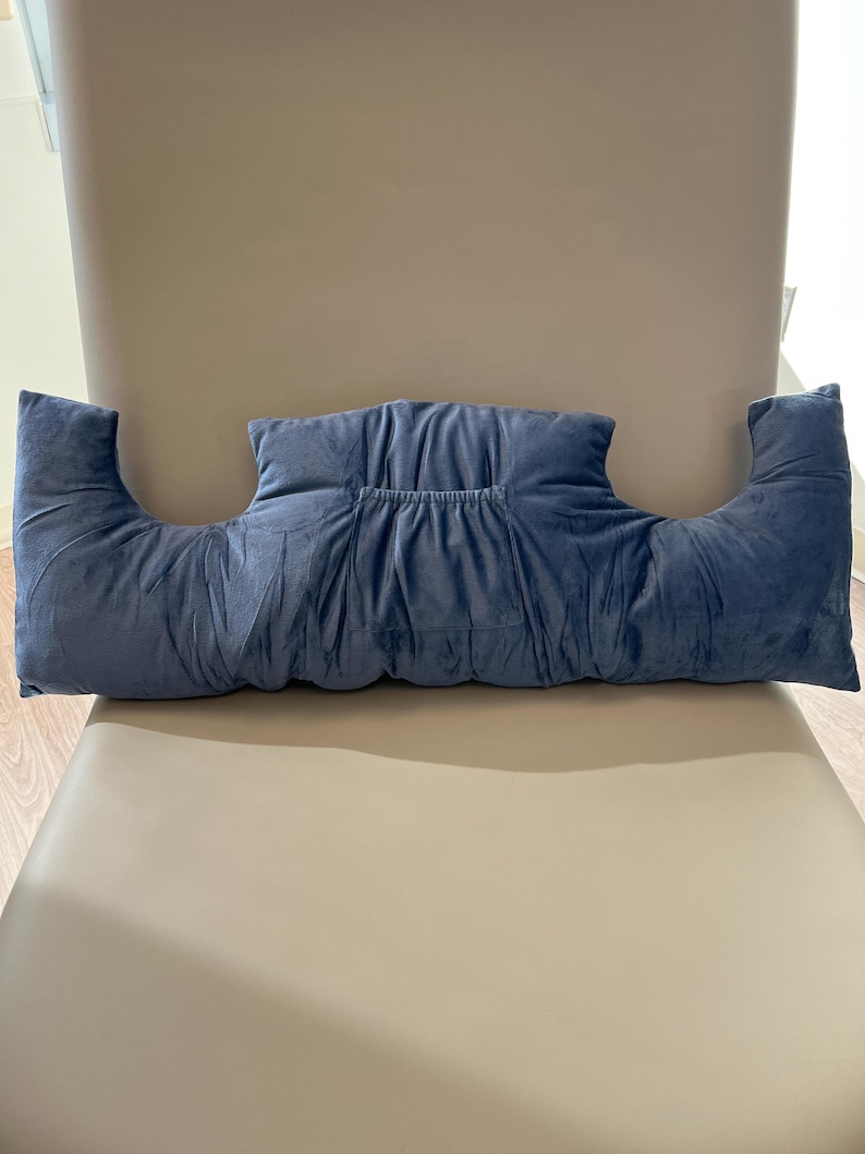 May include: A blue velvet pillow with armrests. The pillow is designed to provide support for the arms and neck while sitting.