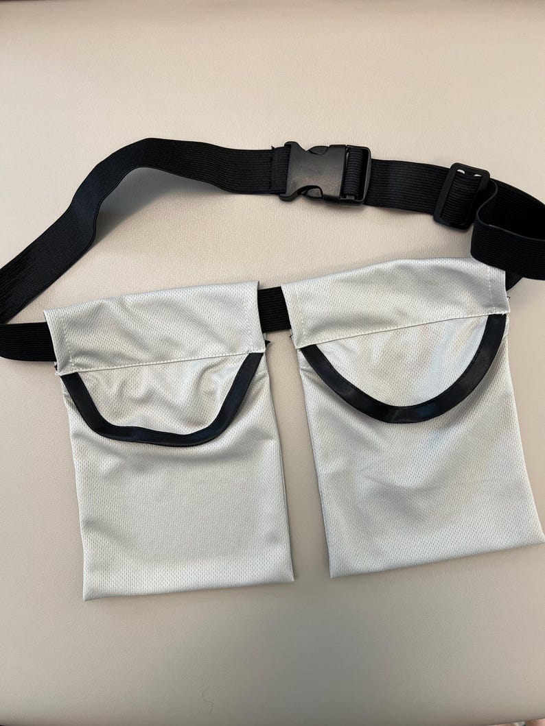 May include: A silver-colored utility belt with two pockets and a black adjustable strap with a buckle.