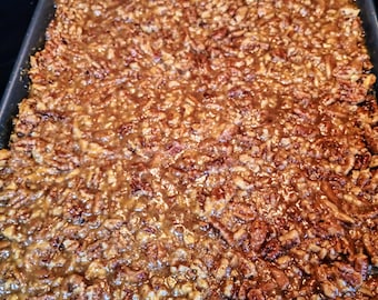 May include: A close-up of a baking pan filled with a pecan pie. The pecans are evenly distributed and covered in a golden brown caramel sauce.