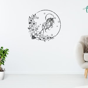 May include: Black and white silhouette of a jellyfish with floral accents in a circle. The design is on a white wall with a potted plant and a white couch in the background.