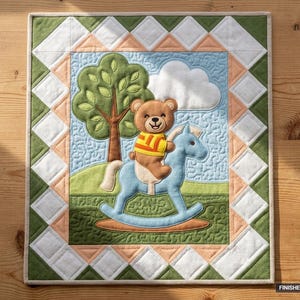 Könnte beinhalten: Ein rechteckiger, gesteppter Wandbehang mit einer zentralen Applikation eines braunen Teddybären in einem gelb-orange gestreiften Shirt, der auf einem hellblauen Schaukelpferd reitet. Die Szene zeigt einen grünen Baum, eine weiße Wolke und eine grüne Landschaft. Der Rand besteht aus weißen und pfirsichfarbenen Rauten. Der Text FINISHED SIZE 36" x 42" ist in der Ecke aufgedruckt.