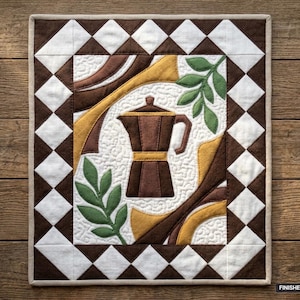 May include: A rectangular fabric wall hanging featuring a central brown moka pot appliqué on a white stippled background, flanked by green leaves and gold curves. The border consists of brown and white diamond shapes. Finished size 36" x 42".