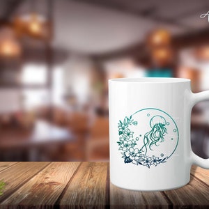 May include: White ceramic mug with a green and blue gradient design featuring a jellyfish and floral illustration. The design is centered on the mug and includes the text "Arga".