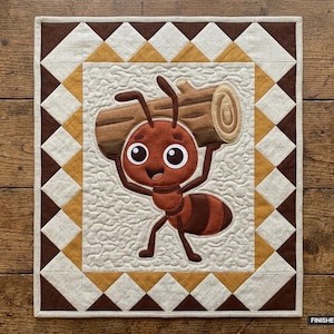 May include: A rectangular quilt featuring a central applique of a brown ant carrying a wooden log. The quilt has a cream-colored background with a stippled texture, surrounded by a border of brown and gold triangles. Finished size 36 inches by 42 inches.