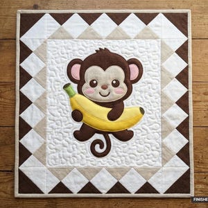 Könnte beinhalten: Ein quadratischer Quilt mit einer zentralen Applikation eines braunen Affen, der eine gelbe Banane auf einem weiß gestippelten Hintergrund hält. Der Rand besteht aus einem geometrischen Muster aus braunen, beigen und weißen Dreiecken. Die fertige Größe beträgt 91,44 cm mal 106,68 cm.