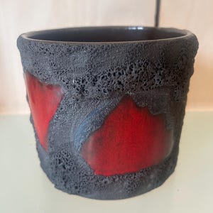 May include: A set of three ceramic mugs with a speckled, matte finish. The mugs are in shades of cream, light grey, and dark grey. Each mug has a simple, minimalist design, ideal for coffee or tea.