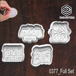 May include: Four white plastic cookie cutters with text: "Best Teacher Ever", "And so the adventure begins", "Class of 2023", and "Dream Big". The cutters are on a dark wood surface. The text "0377_Full Set" is at the bottom.