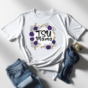 May include: White t-shirt with a floral wreath design and the text "TSU Mama" in black lettering.