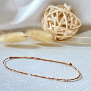 May include: A brown braided cord bracelet with a silver bead accent.
