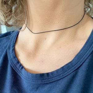 May include: A simple black choker necklace made of thin string.