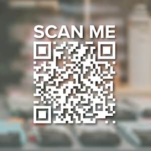 May include: A white QR code with the text "SCAN ME" above it. The code is on a blurry background of a store or shop.