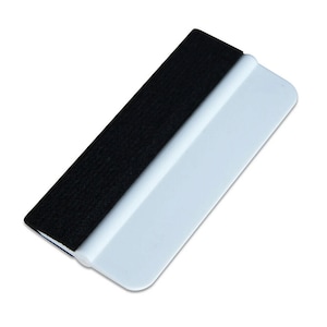 Puede incluir: Una escobilla de goma negra y blanca con un borde de fieltro suave. La escobilla de goma está hecha de plástico y tiene un mango blanco.