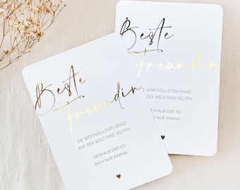 May include: Two white cards with gold lettering that reads "Beste Freundin" and "Beste Freundin". The text on the cards says "Die wertvollsten Dinge auf der Welt sind selten. Deshalb gibt es dich nur einmal." and "Die wertvollsten Dinge der Welt sind selten. Deshalb gibt es dich nur einmal."