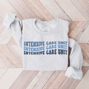 May include: A gray sweatshirt with the text "INTENSIVE CARE UNIT" repeated three times in a blue and white gradient font.