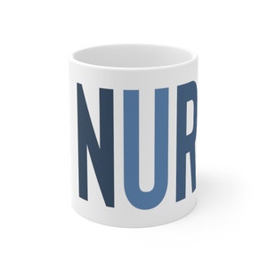以下が含まれることがあります： 白いセラミック製のマグカップに、青と濃い青の文字で「NUR」と書かれています。