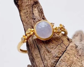 May include: A delicate gold ring with a lavender jade gemstone and small gold flower accents.