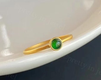 May include: A gold ring with a green gemstone. The ring is simple and elegant.