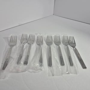 May include: A set of ten silver forks packaged in clear plastic. The forks have a textured design and are arranged in two rows of five.