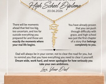 May include: A graduation gift. A gold-coloured necklace with a graduation cap pendant and the name "Stephen" is displayed on a clear acrylic block with a wooden base. Text reads "Congratulations on your High School Diploma".