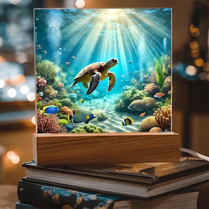 May include: A wooden lamp base with a glass shade featuring a colorful underwater scene. The scene includes a sea turtle swimming through coral reefs and colorful fish. The lamp base is a natural wood color.