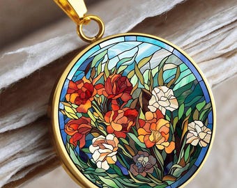 May include: A gold pendant necklace with a circular, stained-glass effect design. The pendant showcases a floral arrangement in red, orange, white, and green, set against a blue backdrop. The necklace has a fine gold chain.
