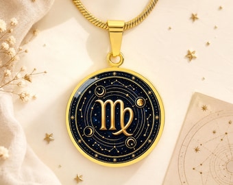 May include: A gold-toned circular pendant necklace featuring the Virgo zodiac symbol in gold against a dark blue celestial background with stars, moons, and planetary rings, suspended from a matching gold-toned snake chain necklace.