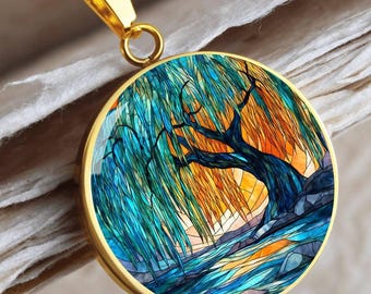 May include: Gold pendant necklace with a circular pendant displaying a colourful willow tree design. The pendant has a gold frame and a detailed image of a tree with blue and green leaves, set against an orange and yellow background.