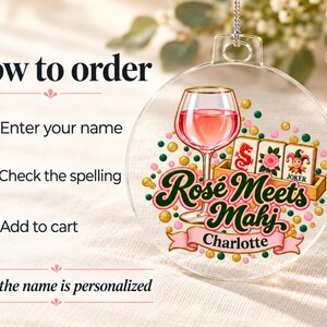 Op de afbeelding: Een doorzichtige ronde acryl hanger met een afbeelding van een wijnglas gevuld met roze vloeistof, drie mahjongtegels en de tekst Ros&eacute; Meets Mahj. Een roze banner eronder toont de naam Charlotte, omringd door gouden en groene stippen.