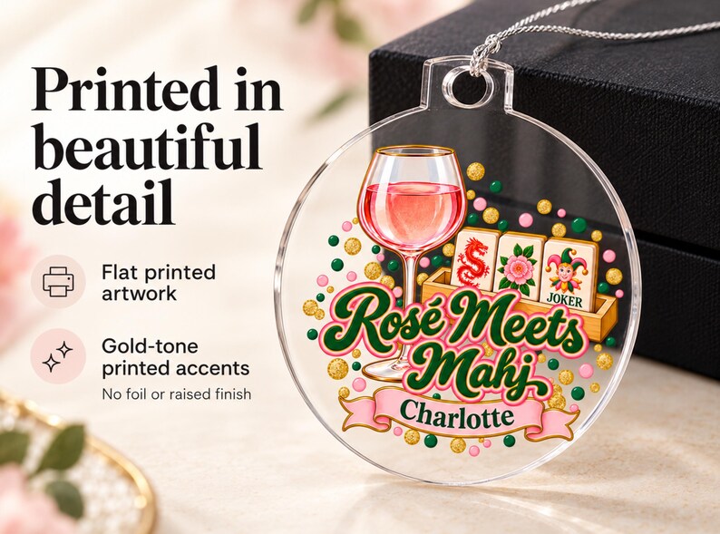 Op de afbeelding: Een ronde, transparante acryl hanger met een opdruk van een wijnglas gevuld met ros&eacute;, mahjongtegels en de tekst "Ros&eacute; Meets Mahj" boven een roze banner met de naam "Charlotte". Het ontwerp bevat goudkleurige accenten.