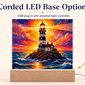K&ouml;nnte beinhalten: Eine quadratische Acrylplatte mit einer Leuchtturm-Illustration auf einem Holzsockel. Der Text lautet Corded LED Base Option und USB plug-in with attached light controller. Das Bild zeigt einen Leuchtturm auf einer felsigen Insel bei Sonnenuntergang.