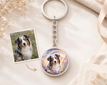 May include: A silver metal keyring featuring a circular pendant with a custom illustration of an Australian Shepherd dog surrounded by flowers, a rainbow, and a crescent moon, attached to a standard split ring by a short metal chain.