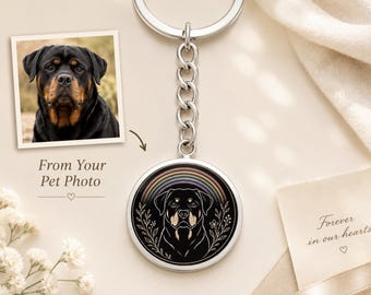 May include: A silver-toned circular keyring featuring a black and tan Rottweiler illustration framed by a rainbow and botanical line art. The keyring includes a metal chain and ring. Text on the image reads: From Your Pet Photo and Forever in our hearts.