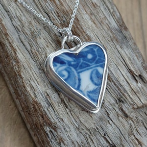 May include: A silver heart-shaped pendant necklace with a blue and white porcelain design.
