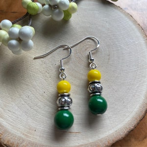 May include: A pair of dangle earrings with green and yellow beads and silver accents.