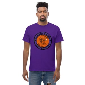 以下が含まれることがあります： 紫色のTシャツ。円形のグラフィックには、タバコを持ったリスが描かれています。グラフィックはオレンジと黒で、「RODENT BASED 100% Quality LEAN PRODUCTS 100% Lean!」と書かれています。シャツは無地で、半袖です。