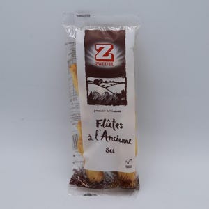 Könnte beinhalten: Eine Packung Zweifel Flûtes à l'Ancienne Salzbrezel. Die Verpackung ist braun und weiß mit einem Bild eines Feldes und eines Bauernhauses. Die Brezel sind durch die transparente Plastikverpackung sichtbar.