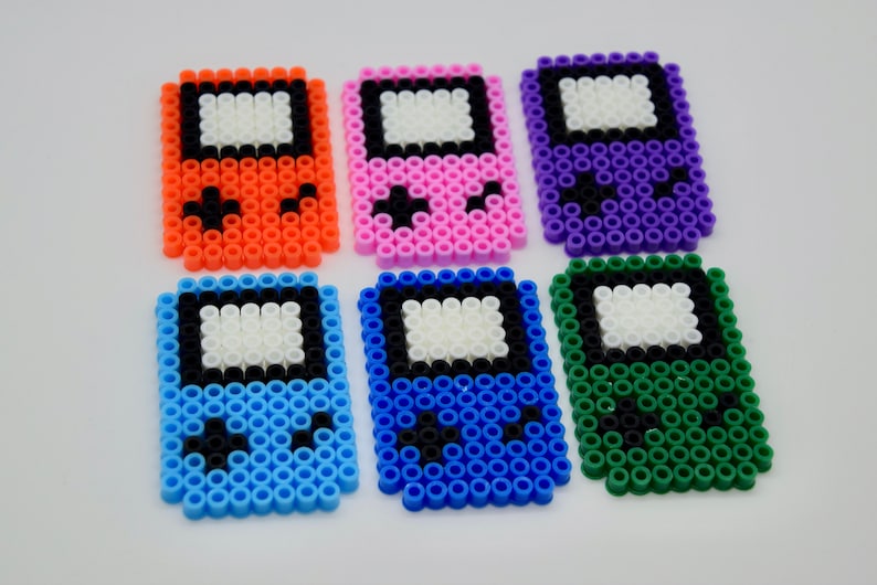 May include: Six colorful pixel art Game Boy style keychains. The keychains are made of plastic beads and come in orange, pink, purple, blue, light blue, and green.