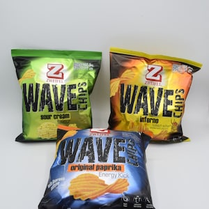 Könnte beinhalten: Drei Packungen Zweifel Wave Kartoffelchips. Die Packungen sind grün, gelb und blau. Die grüne Packung sagt "sauer Sahne Geschmack". Die gelbe Packung sagt "Inferno höllisch scharf" und die blaue Packung sagt "original Paprika Energy Kick".