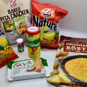 Könnte beinhalten: Eine Auswahl an Kartoffel-Snacks und Zutaten, darunter eine Tüte Zweifel Paprika Kartoffelchips, eine Tüte Zweifel Nature Kartoffelchips, eine Tüte Zweifel Baked Pita Cracker, eine Schachtel Blévita Sandwich Cracker, eine Packung Original Rösti und ein kleines Behältnis mit Knorr Aromat Gewürz.