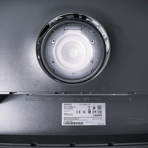Pu&ograve; includere: Il retro di un'unit&agrave; di visualizzazione a colori Samsung con un'apertura circolare per il montaggio. L'unit&agrave; ha un'etichetta con i loghi CE, UKCA e HDMI.