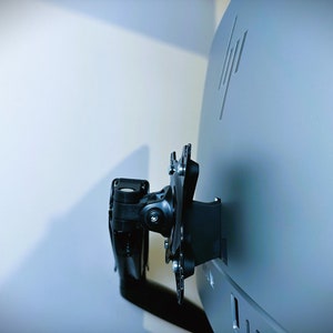 Puede incluir: Un soporte de monitor negro fijado a la parte posterior de un monitor HP gris.