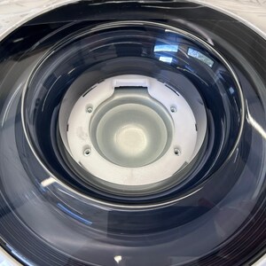 Pu&ograve; includere: Primo piano di un cestello di lavatrice bianco con una guarnizione in gomma nera e un centro in plastica trasparente.