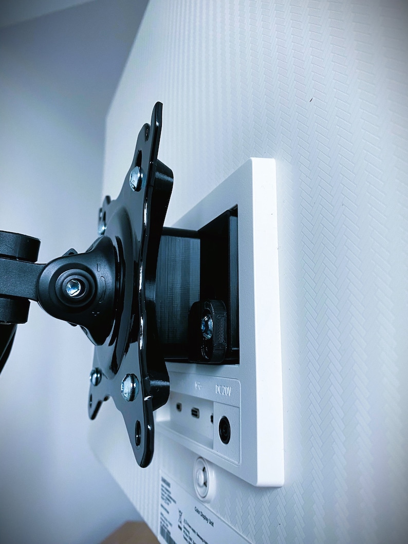 May include: Close-up of the back of a white monitor with a black monitor arm attached. The monitor has a DC 20V power input and a USB port.