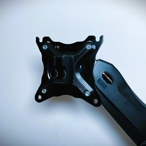 May include: Black metal monitor arm with a VESA mount plate and a swivel arm. The arm is labelled "AVLT" and has a black plastic cover.