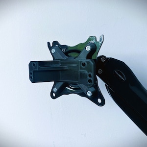 Puede incluir: Brazo de monitor negro con un brazo giratorio y una placa de montaje. El brazo está etiquetado como "InVision".